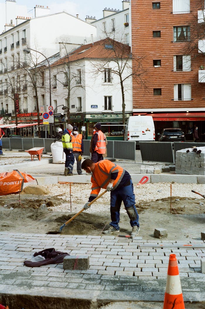 Construction workers in a city setting paving a street under daylight conditions.